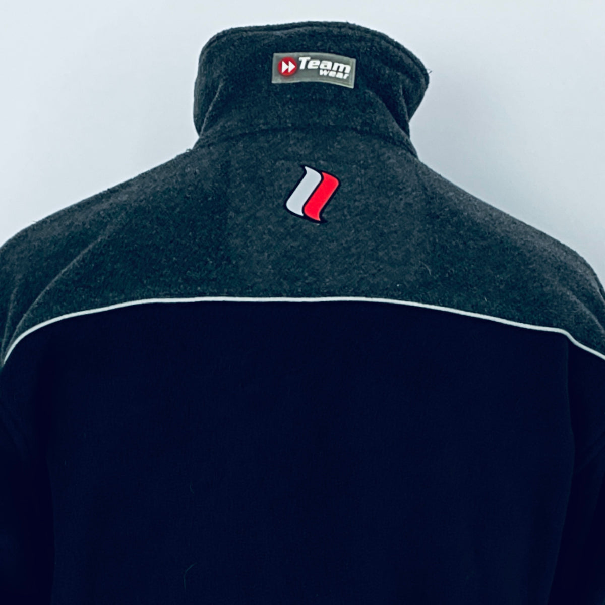 Dark jacket with a logo on the chest against a light gray background