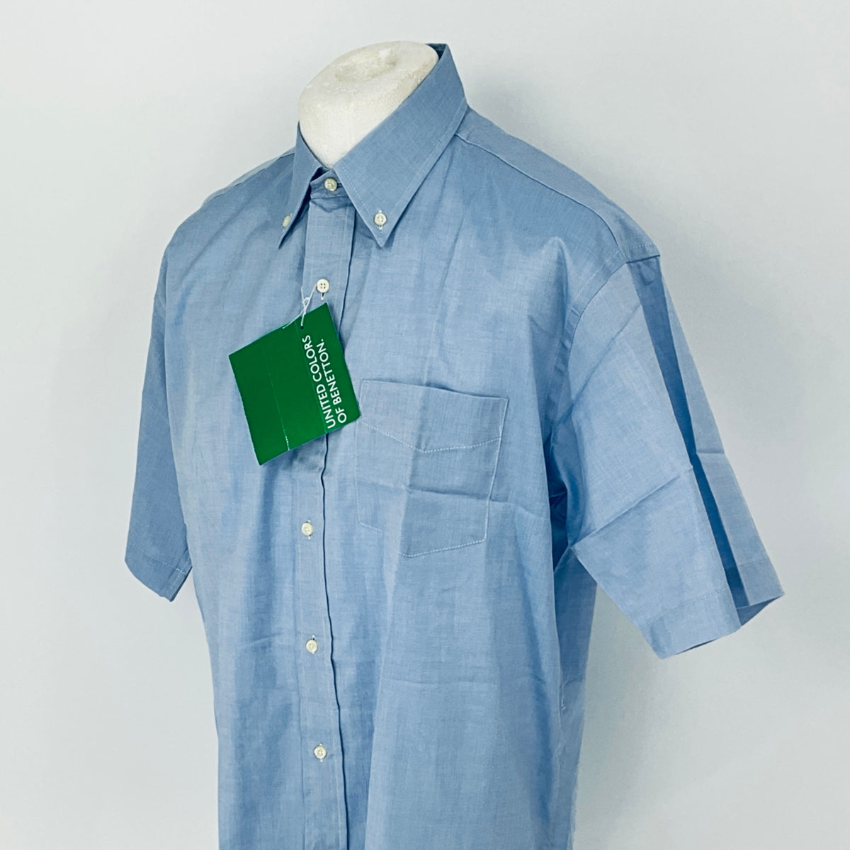 Blue shirt on a mannequin with a green tag against a white background
