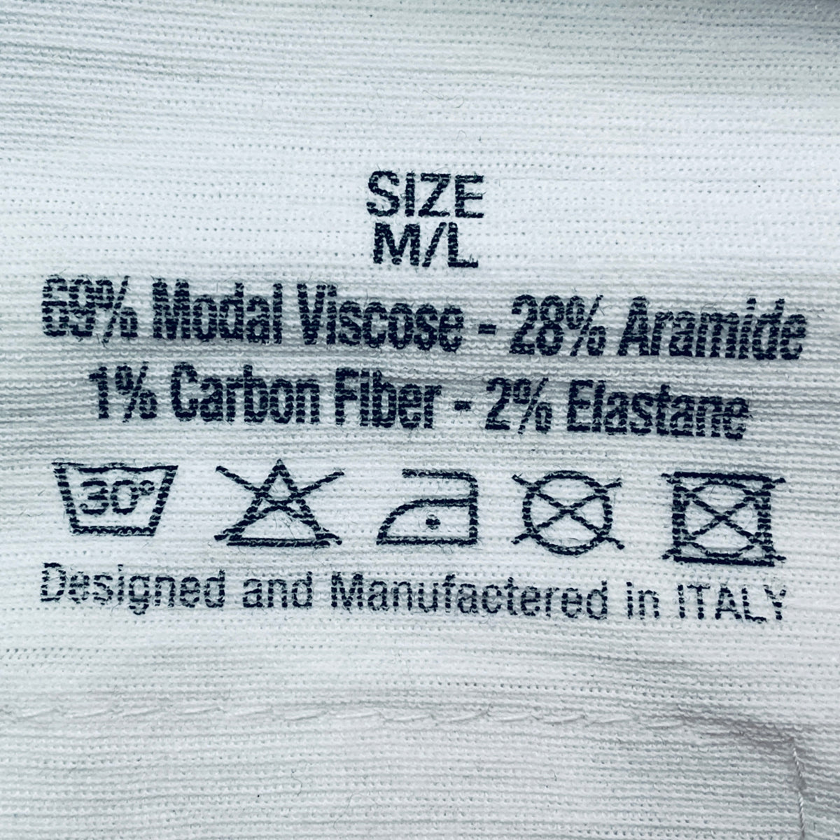 Textile label with material composition and care instructions on a fabric background