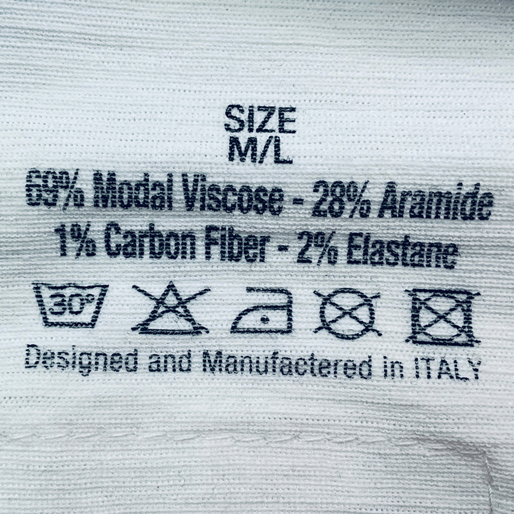 Textile label with material composition and care instructions on a fabric background