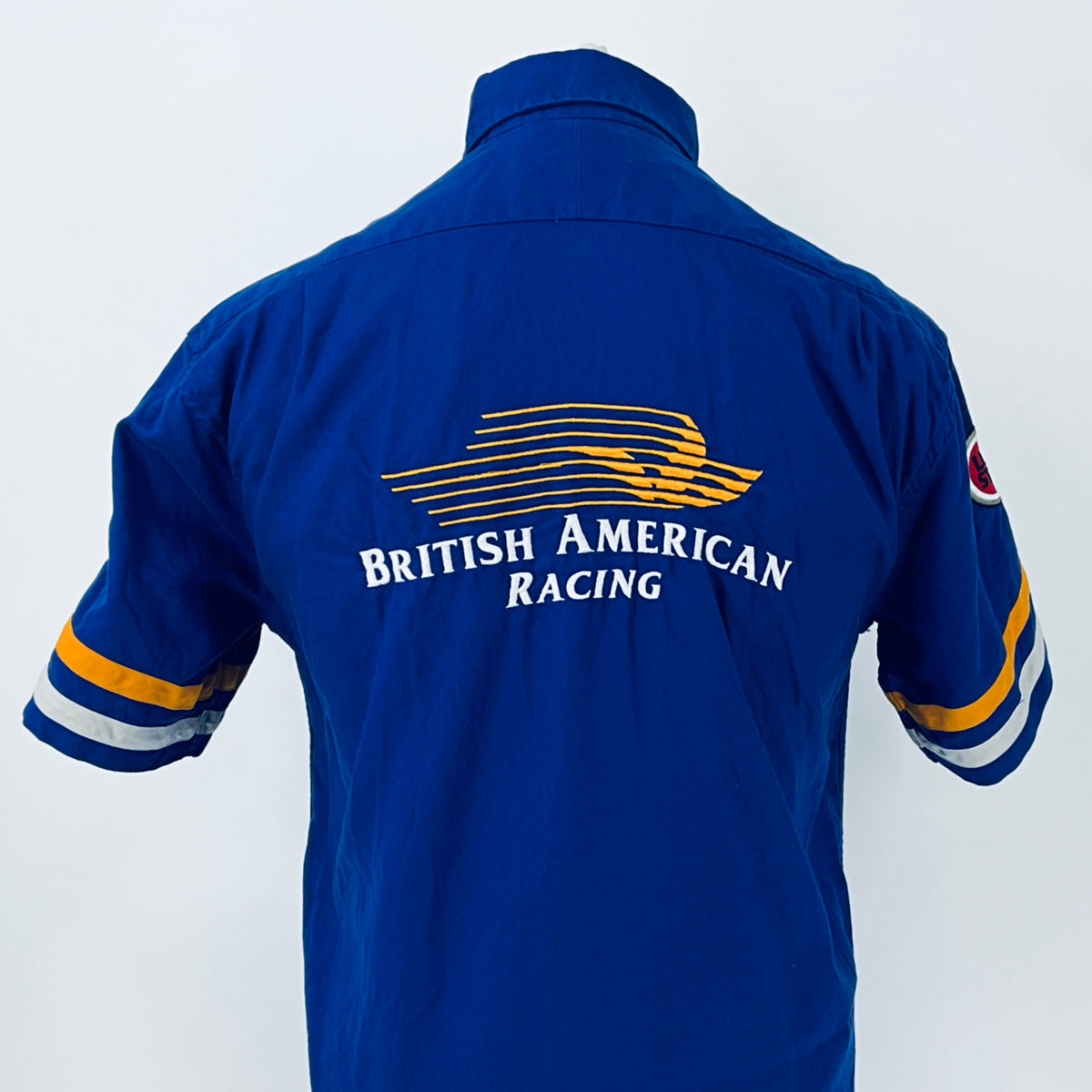 Blue racing shirt back view showing large “British American Racing” logo across shoulders