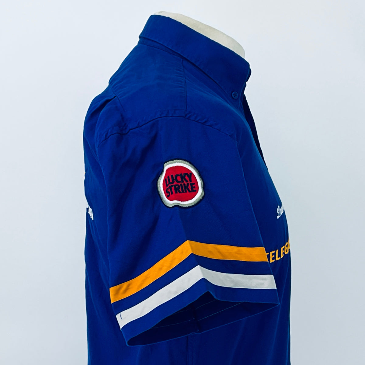 Blue button-up racing shirt back sleeve view with “Lucky Strike” patch and stripes