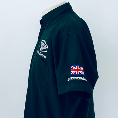 Dark teal polo shirt side view with Team Bentley patch and Dunlop sleeve graphic
