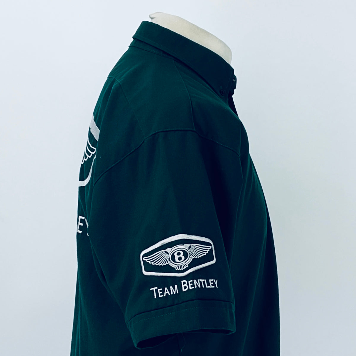 Dark teal polo shirt side view with Team Bentley patch on sleeve