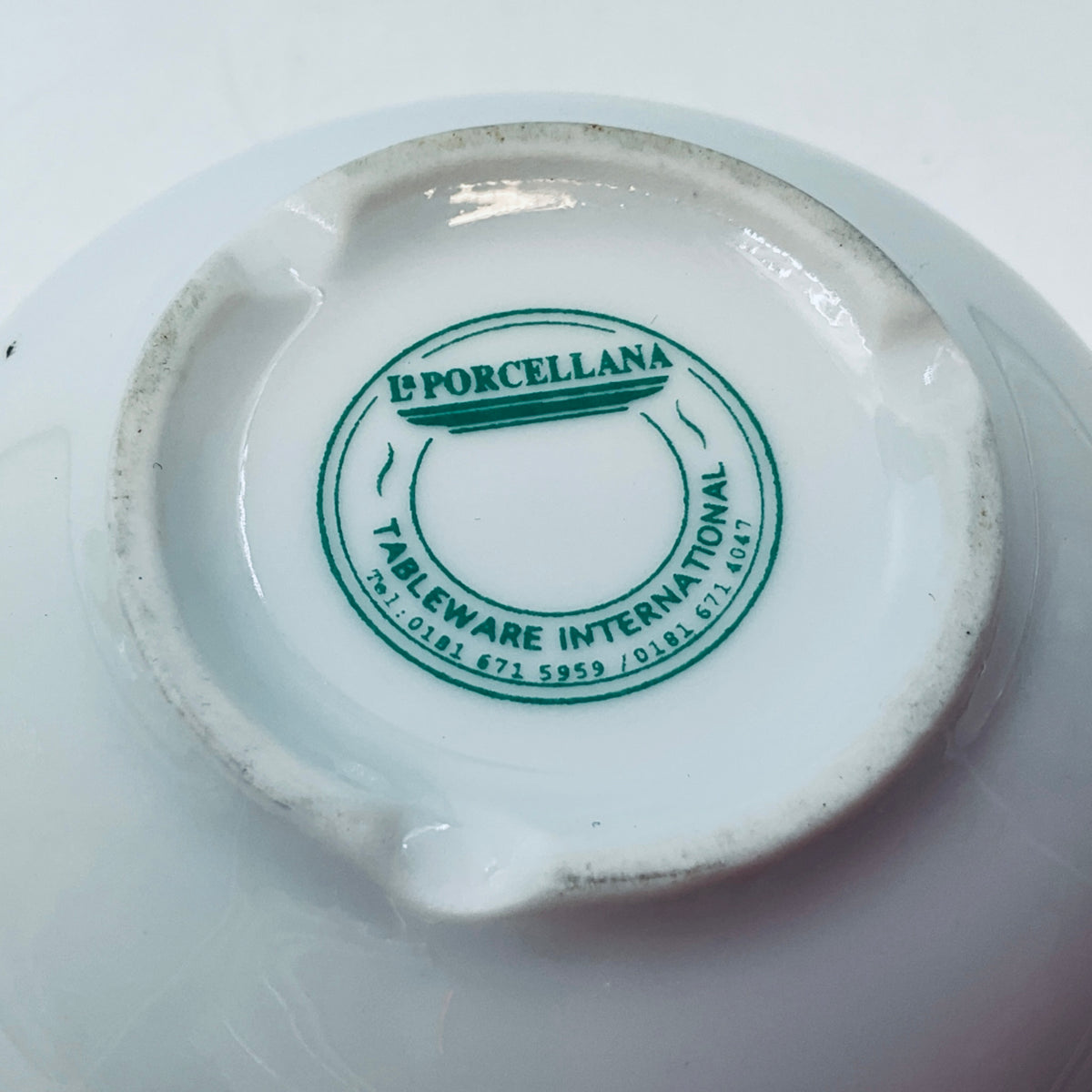Close-up of green L'PORCELLANA tableware international backstamp on base