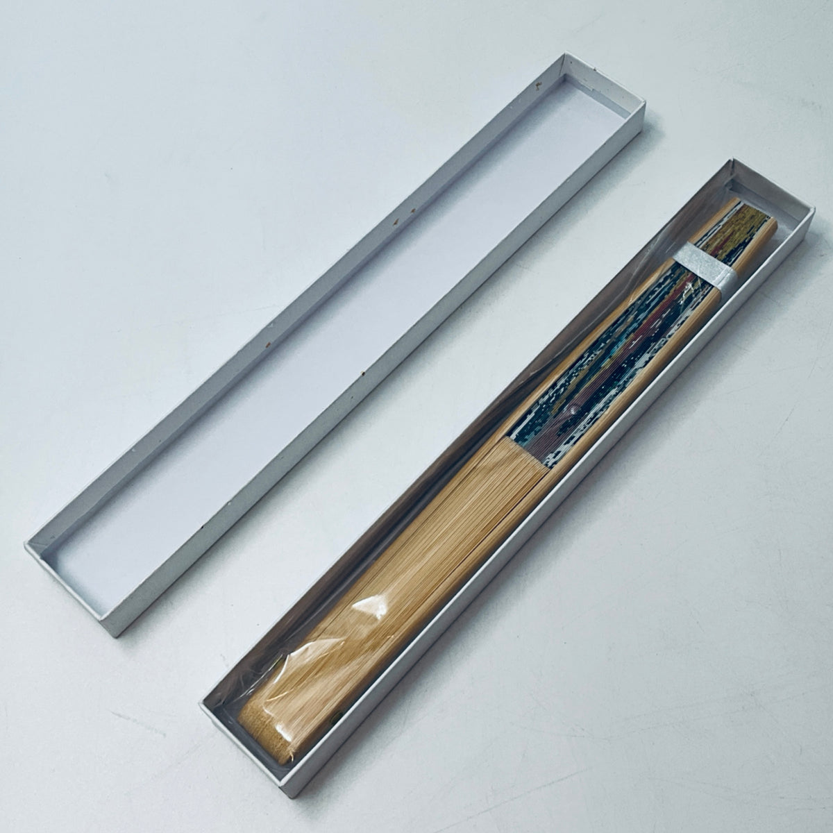Closed folding fan with wooden ribs packaged in a slim gray case
