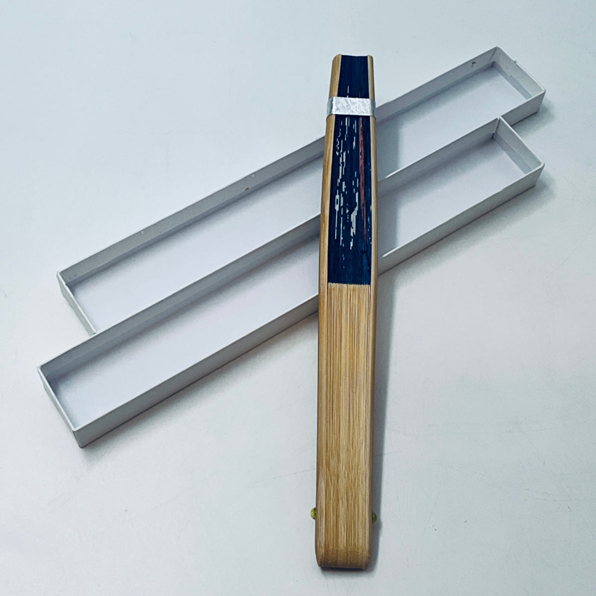 Folding fan closed with wooden handle and blue patterned paper, in slim box