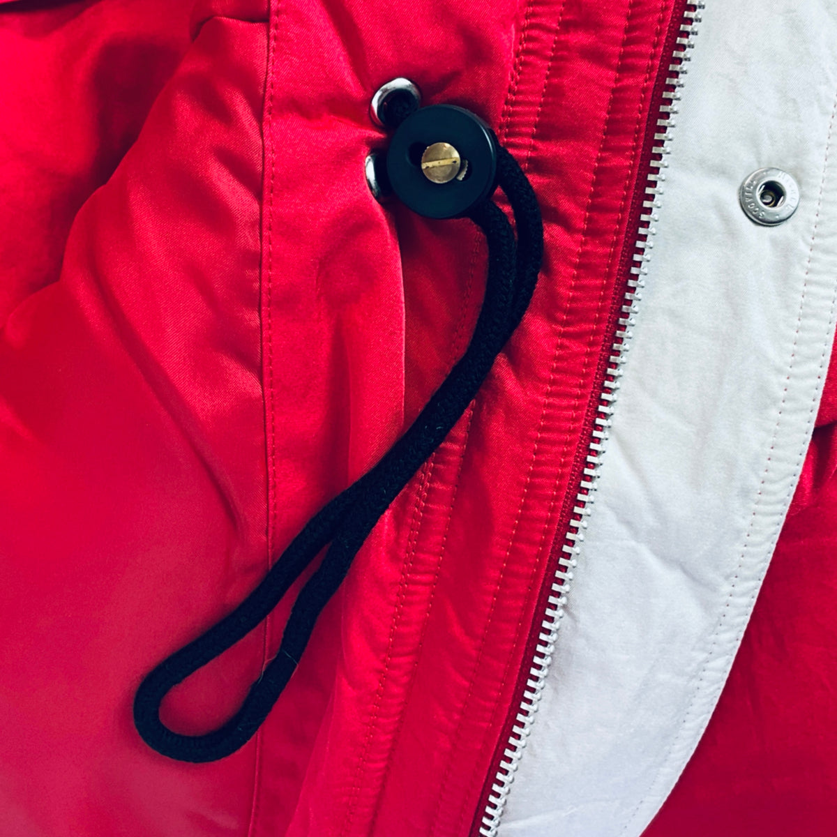 Red and white winter jacket with dark toggle pull and silver zipper hardware