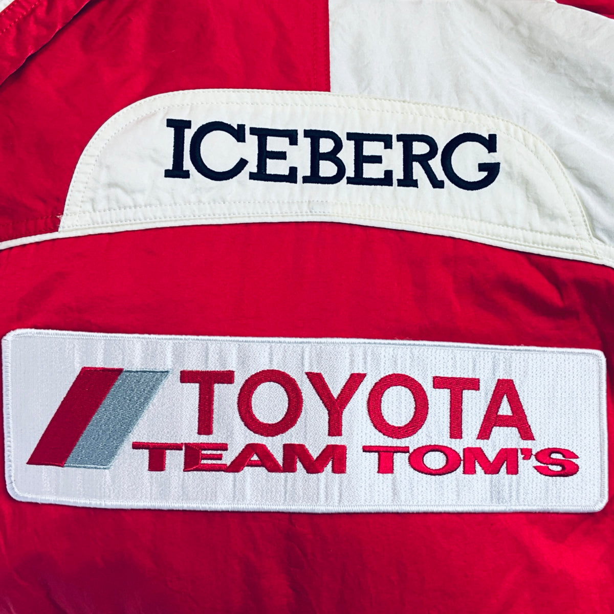 Iceberg logo and Toyota Team TOM'S patch on red-and-white winter parka