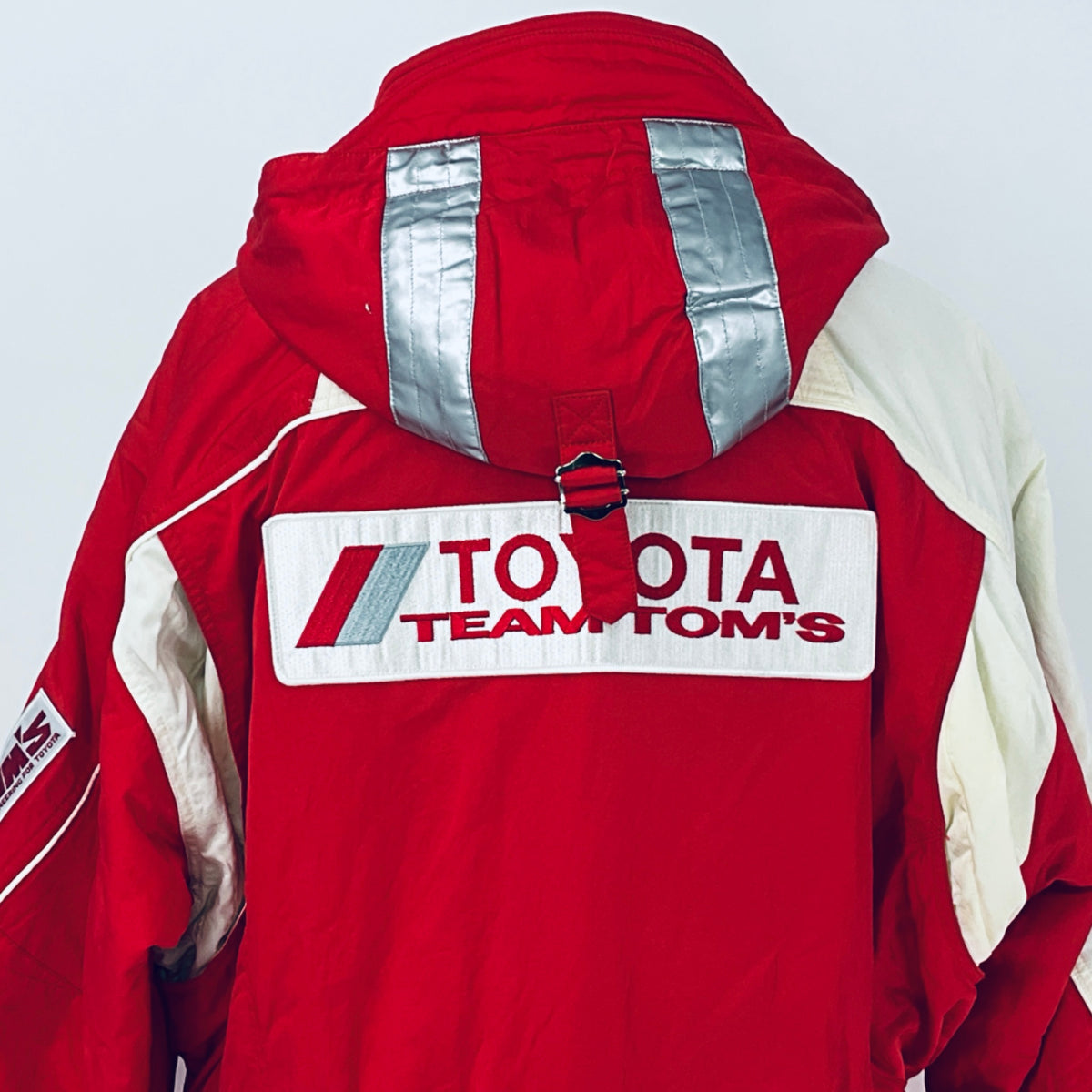 Red winter parka jacket with hood and back Team TOM'S logo across the chest panel