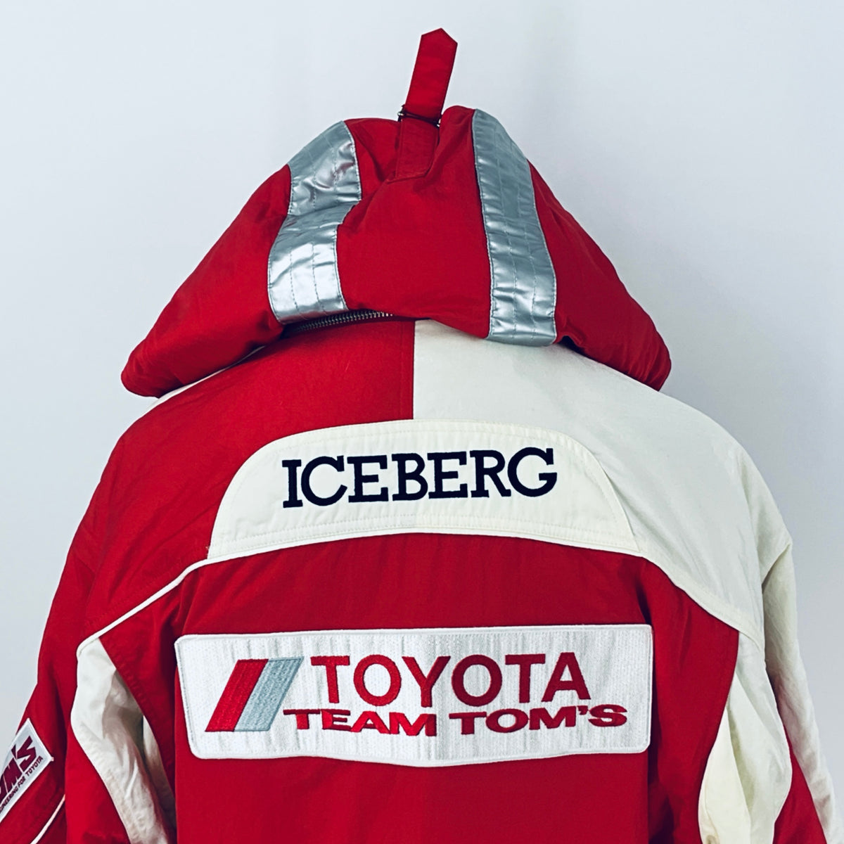 Red and off-white winter parka with hood, ICEBERG logo on the back, and Team TOM'S patch