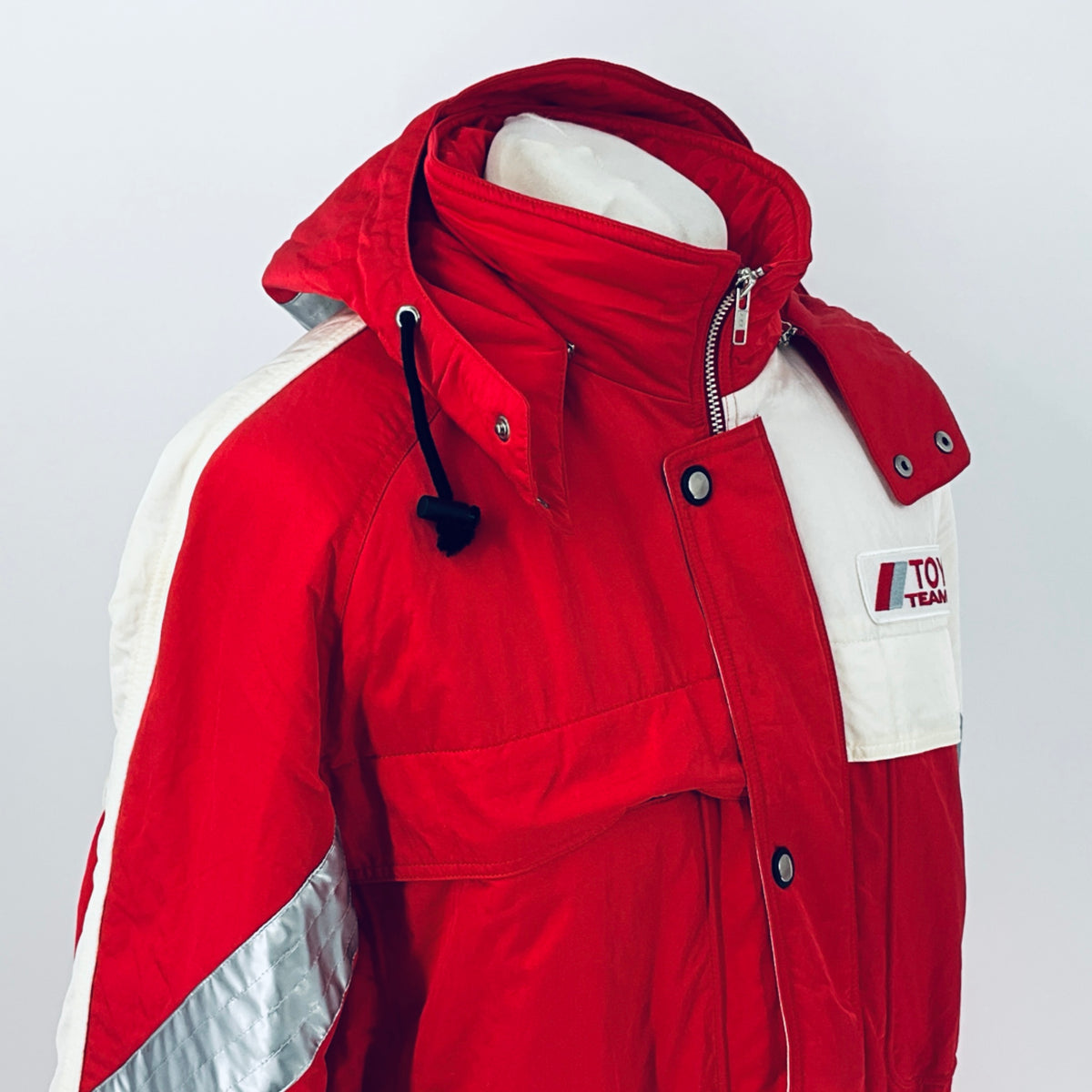 Red winter jacket with hood, white logo patch, zip front and snap button pockets