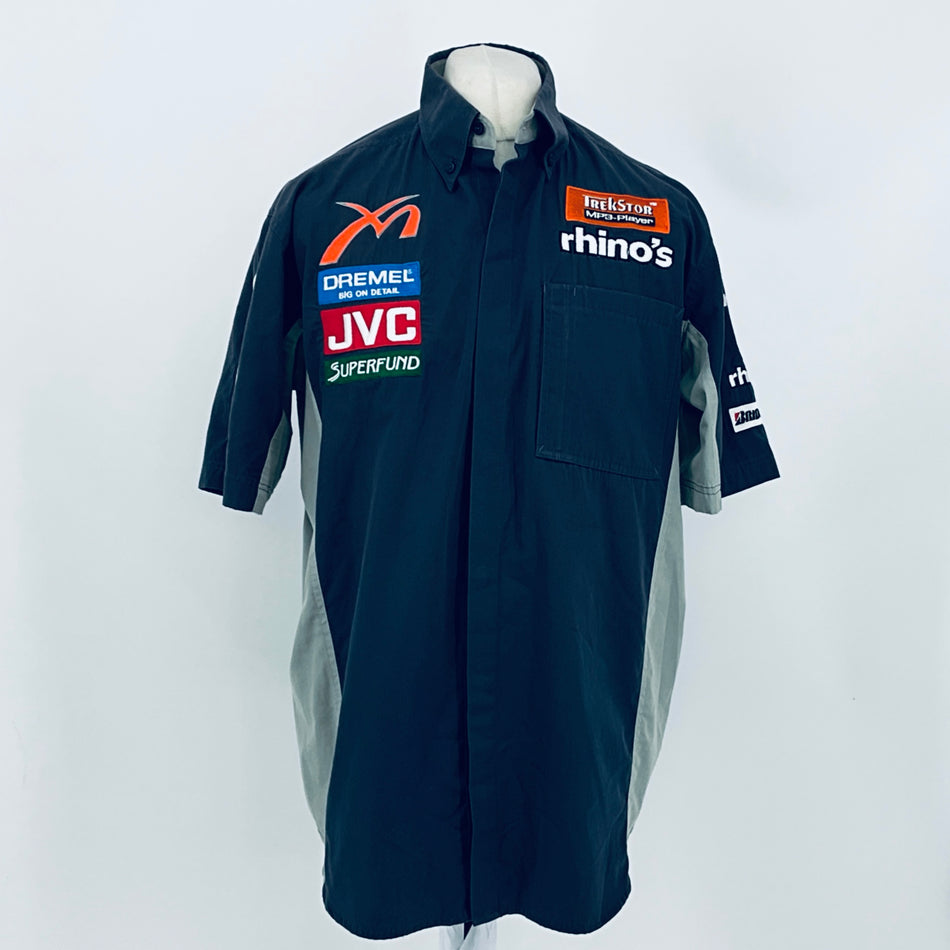 Dark teal short-sleeve racing shirt with button collar and front sponsor patches.