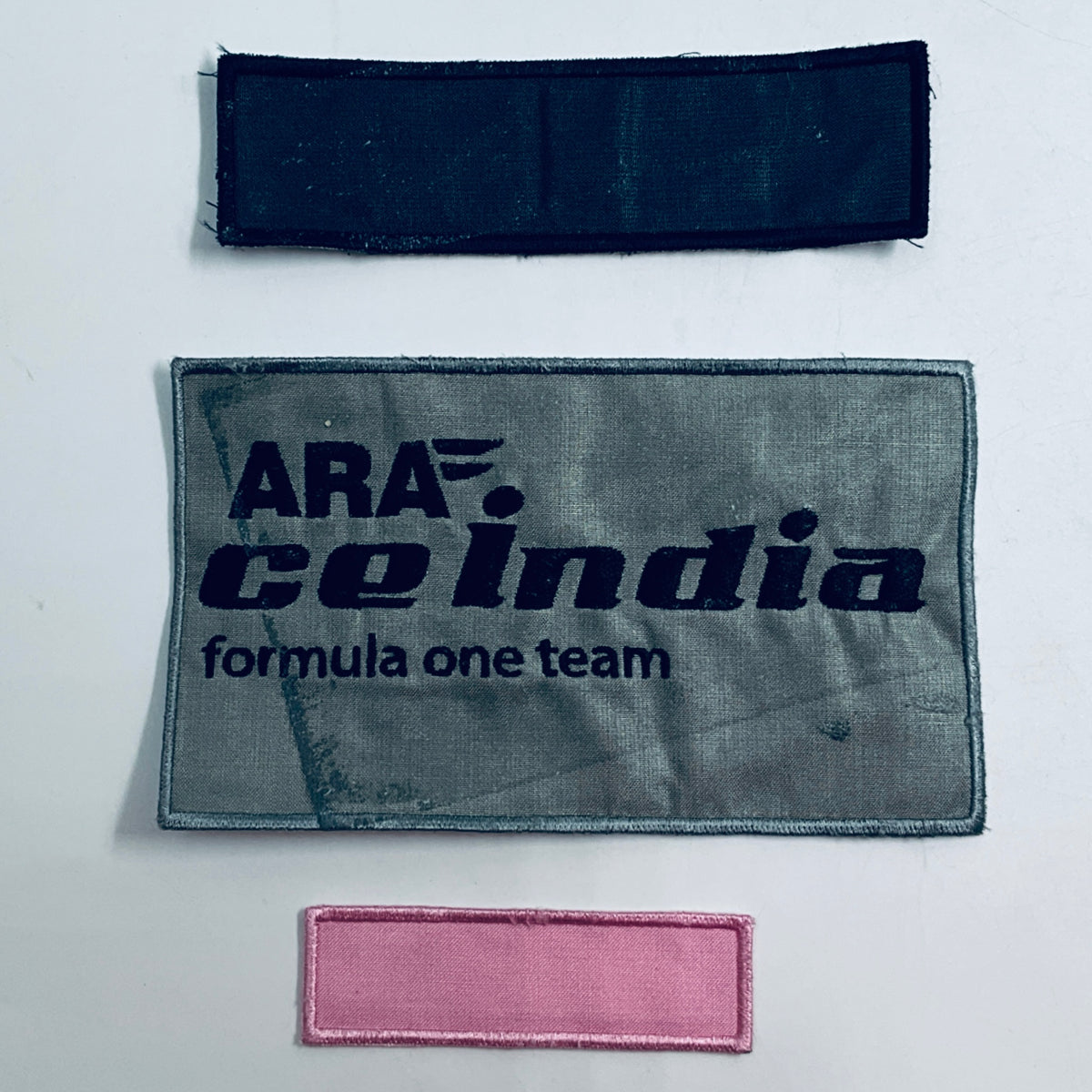 Set of three rectangular fabric patches: navy, gray Formula One team, and pink