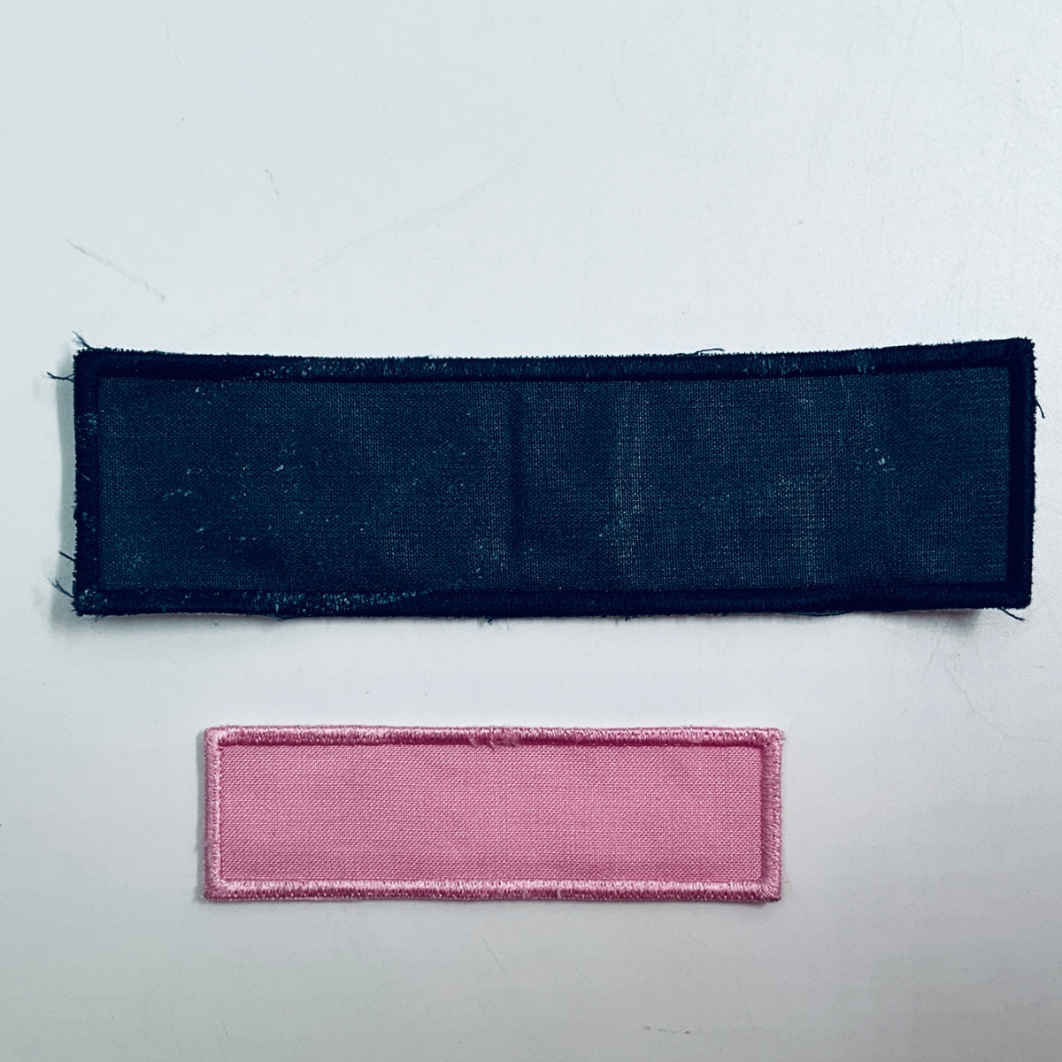 Two rectangular fabric patches: dark navy and pink with stitched border