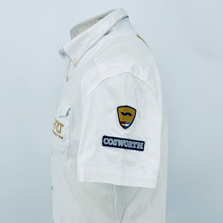 White pit crew shirt viewed from the side, featuring a shield emblem and “COSWORTH” patch.