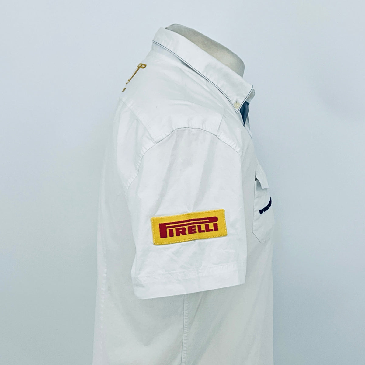 White pit crew shirt side view with “Pirelli” rectangular sleeve patch.