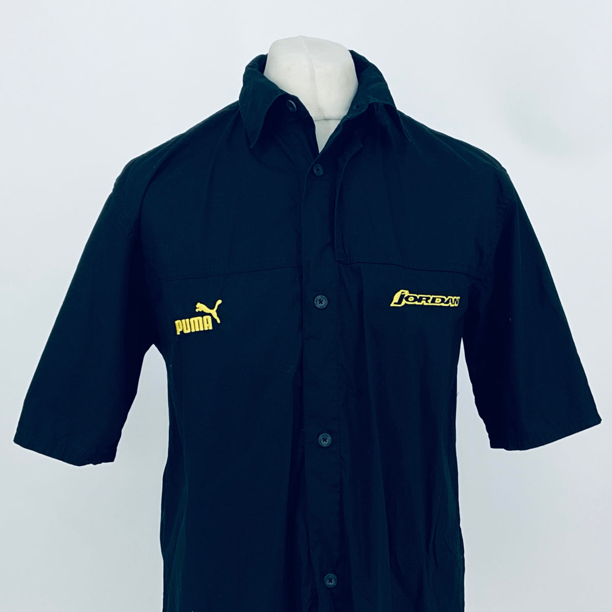Dark navy short-sleeve button-up shirt with collar; front logos including JORDAN on chest.