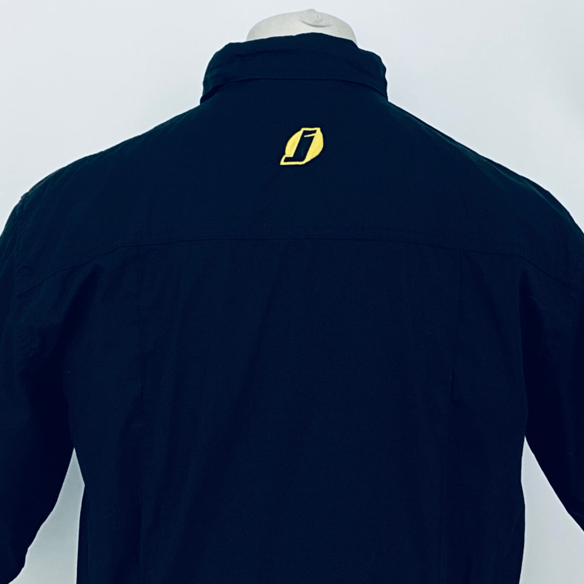Dark navy short-sleeve button-up shirt close back view; yellow emblem centered at upper back.