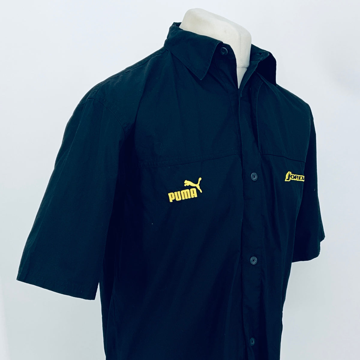 Dark navy short-sleeve button-up shirt, 3/4 view; PUMA logo center front and JORDAN patch.