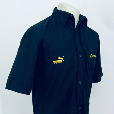 Dark navy short-sleeve button-up shirt, 3/4 view; PUMA logo center front and JORDAN patch.
