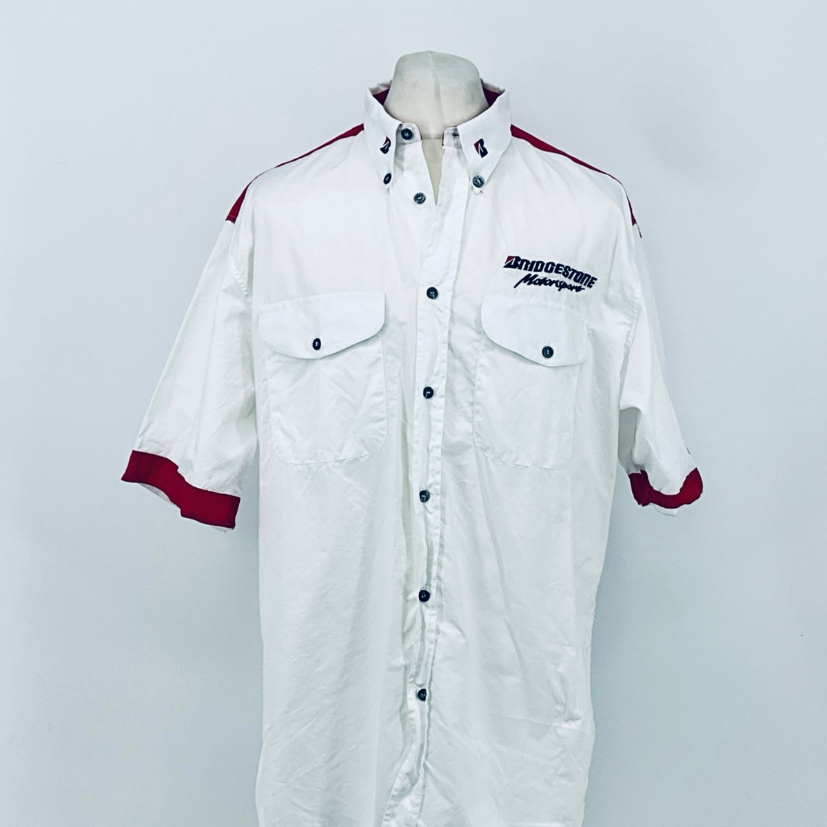 White button-up F1 employee shirt with maroon sleeve cuffs, chest pockets, and logos.
