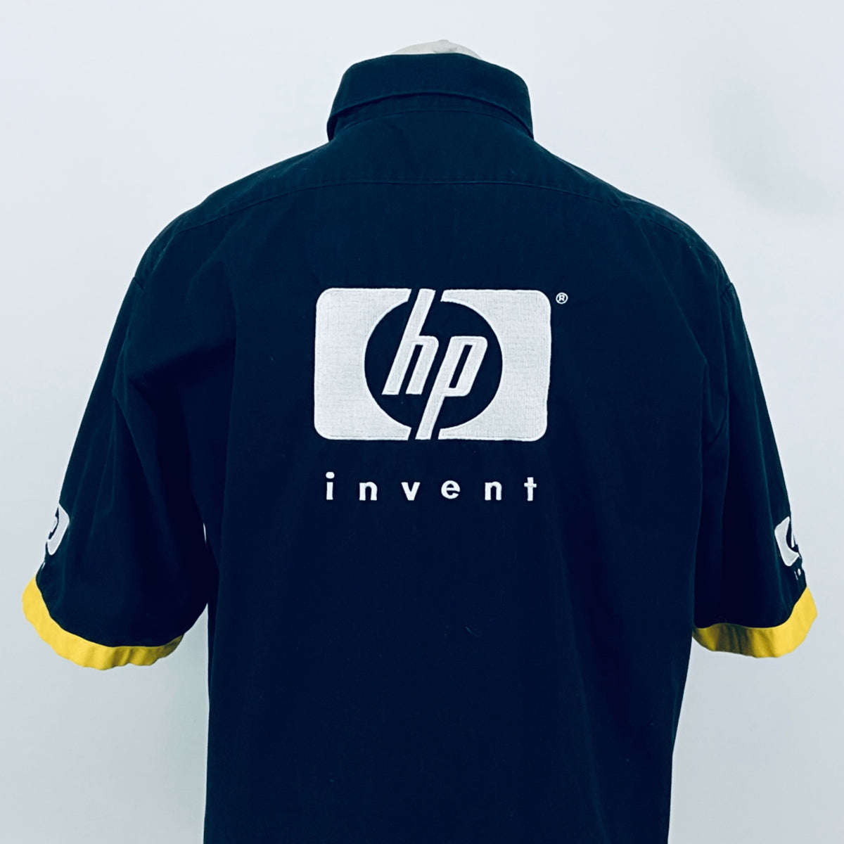 Dark blue team shirt back view with centered hp invent logo and yellow sleeve cuffs