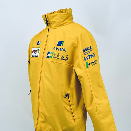 Yellow racing jacket back view with ITC and LAFARGE sponsor logos and hood.