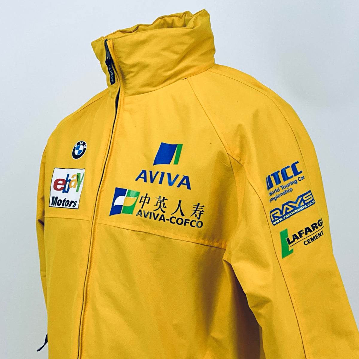 Yellow racing jacket back with ITC and RAYS sponsor patches and AVIVA branding.