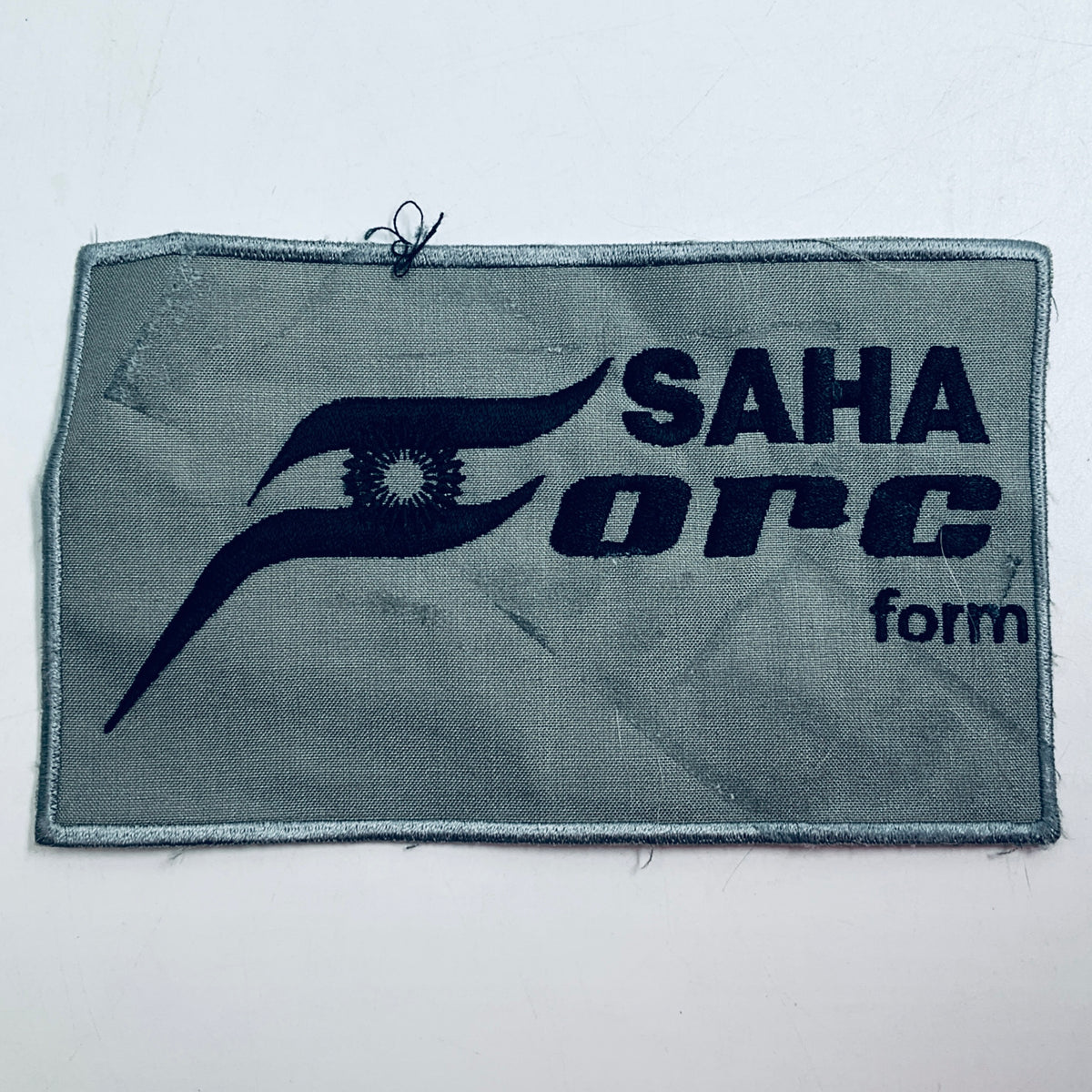 Rectangular embroidered patch with gray fabric and navy SAHA ORCA logo and text.