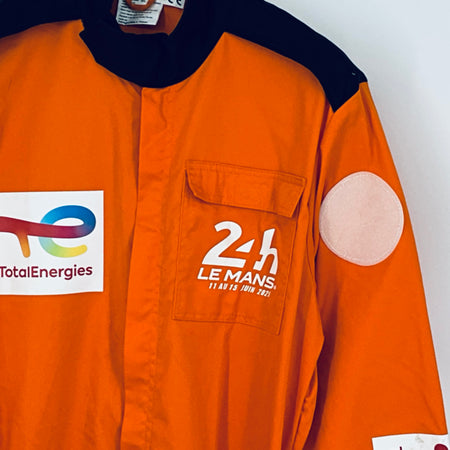 Orange overalls chest panel with 24h Le Mans logo and white round shoulder patch