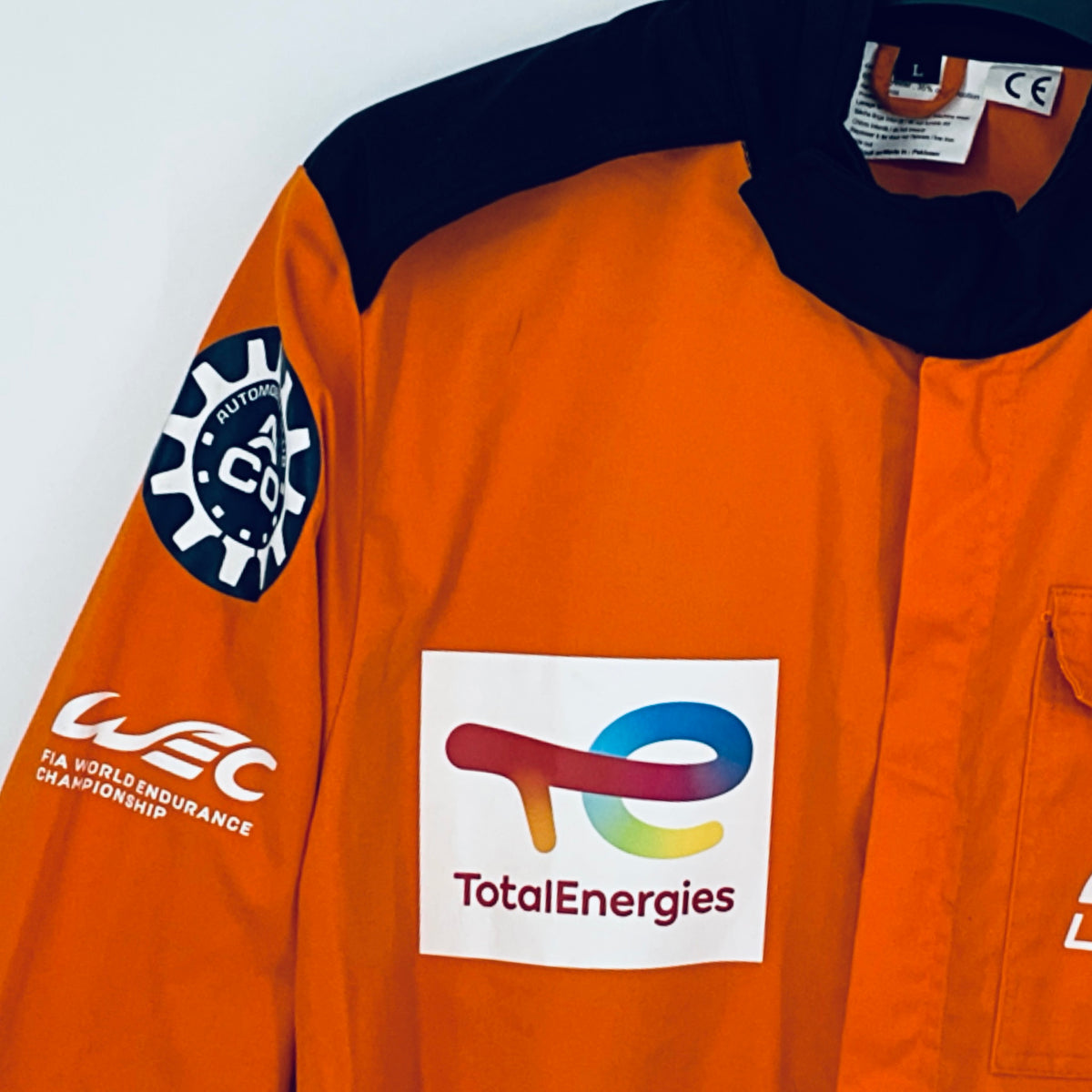 Orange overalls with dark sleeve patch and TotalEnergies logo on front chest