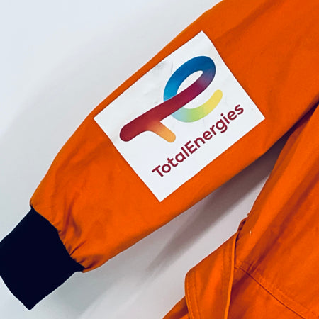 Orange overalls sleeve with TotalEnergies logo label and dark cuff