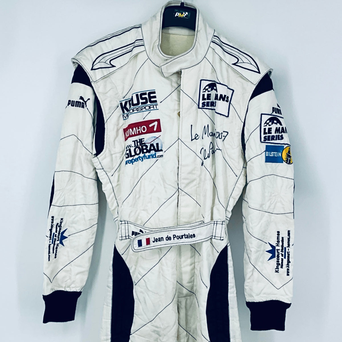 Race-worn driver suit, white with navy side panels and embroidered race patches.