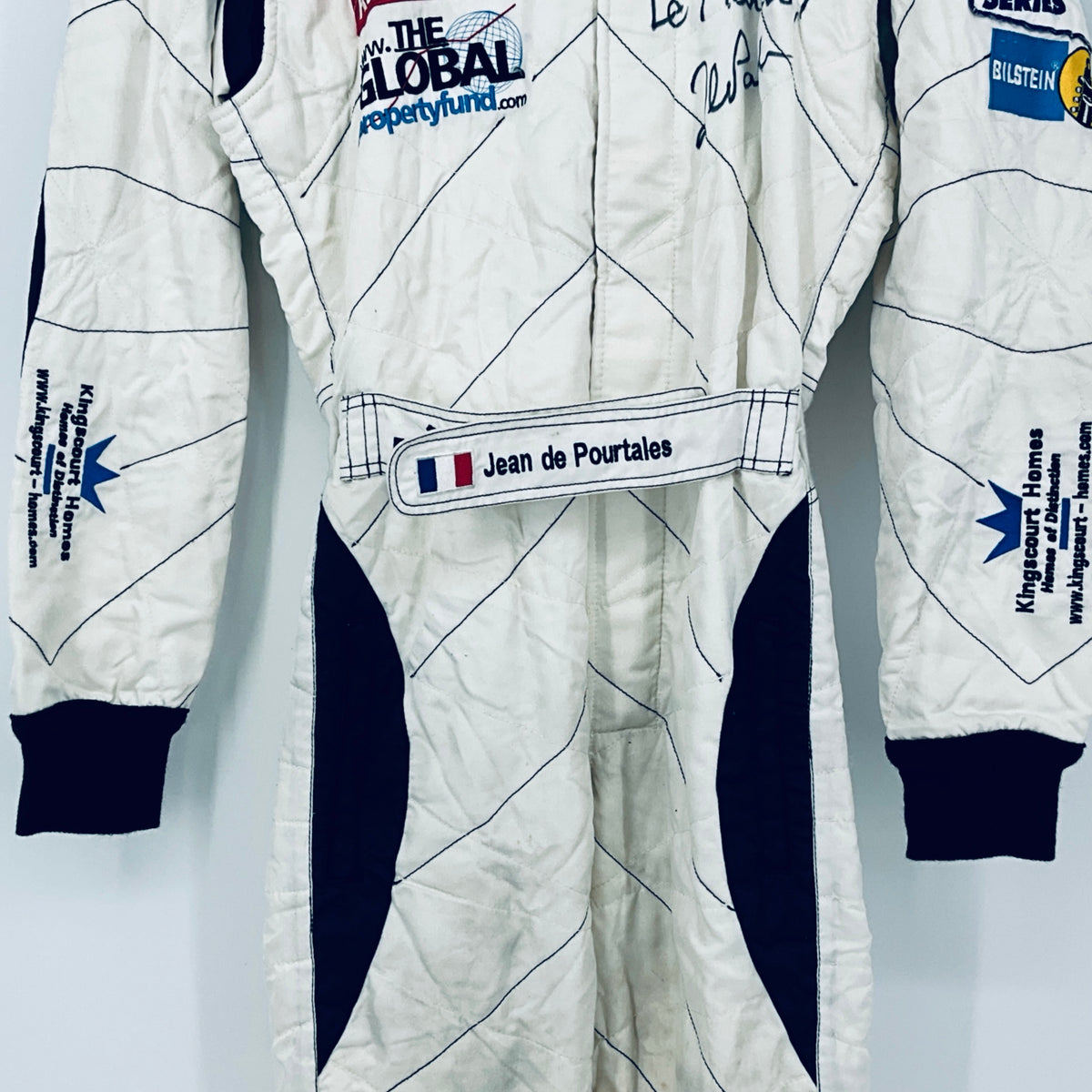 Race-worn driver suit front view: name tab at waist and navy side stripe panels.