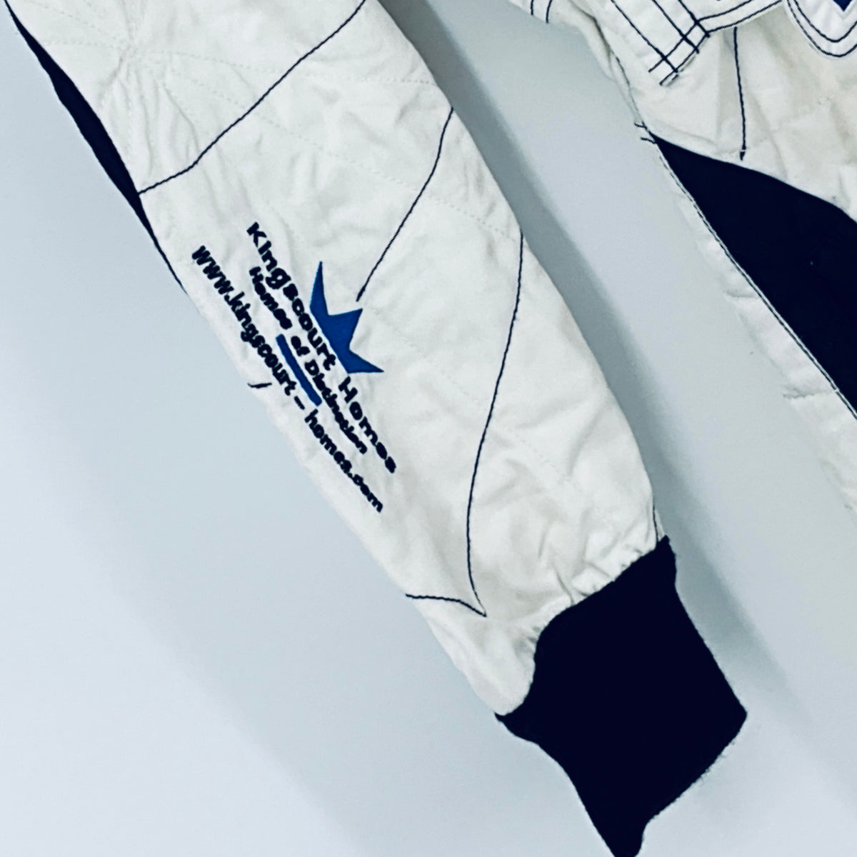 Race-worn driver suit leg close-up with creased white fabric and navy cuff.