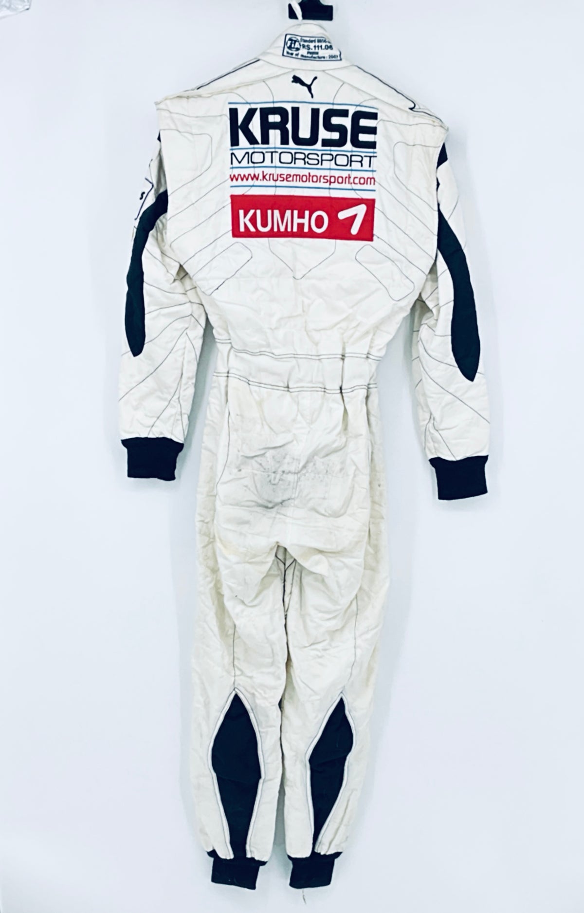 Race-worn driver suit back view: large “KRUSE” and “KUMHO 7” sponsor decals.