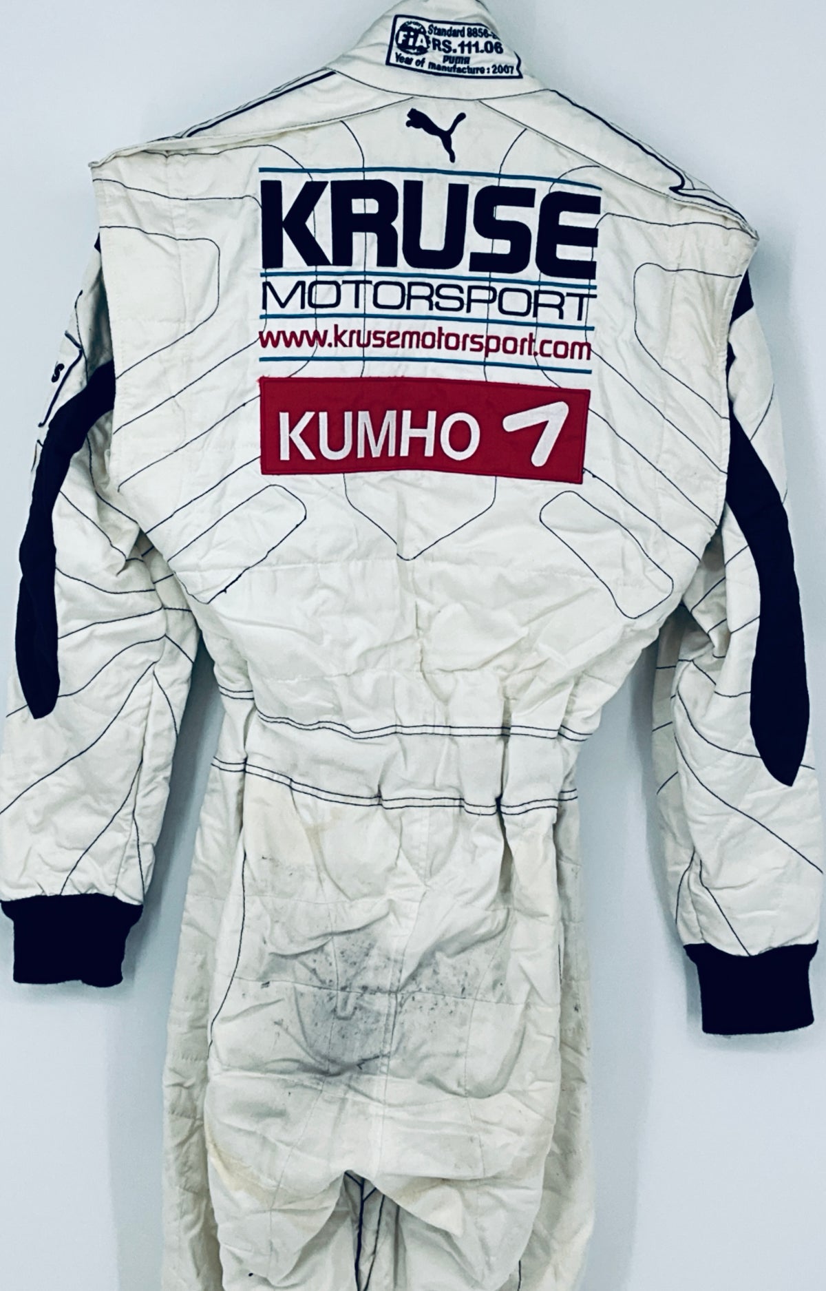 Race-worn driver suit back detail with “KRUSE Motorsports” text and “KUMHO 7” label.