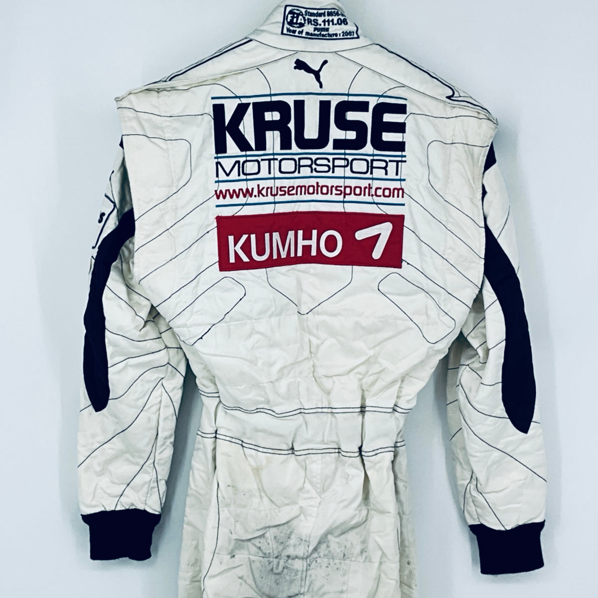 Race-worn driver suit back centered view with sponsor logos and navy sleeve accents.