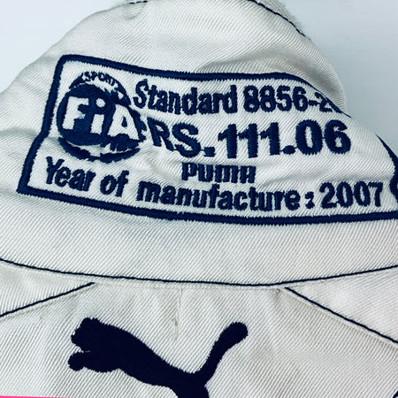 White suit shoulder patch with FIA Standard 8856-11/06 and Puma text