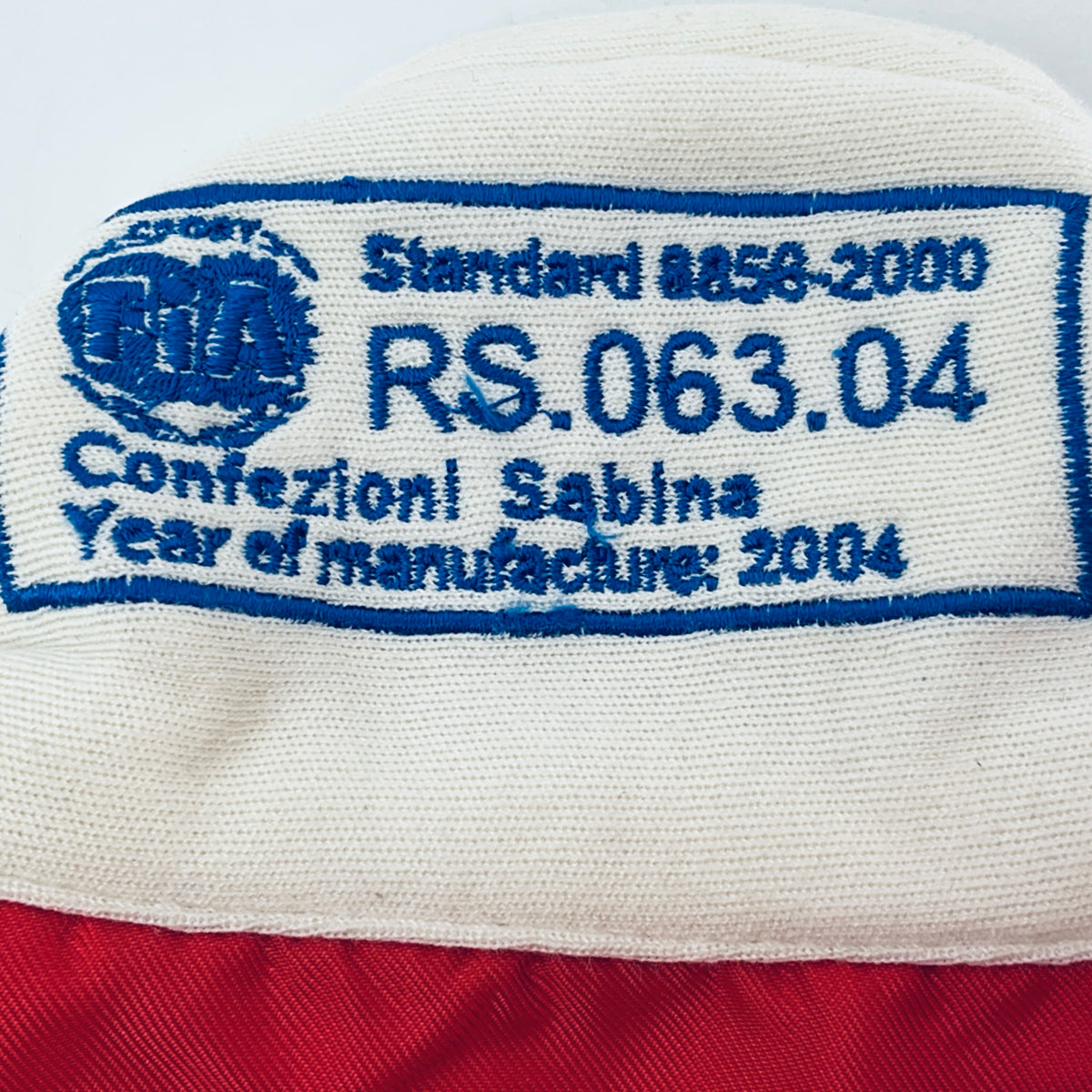 White fabric neck label with blue text: “RS, 003.04” and event/grade details