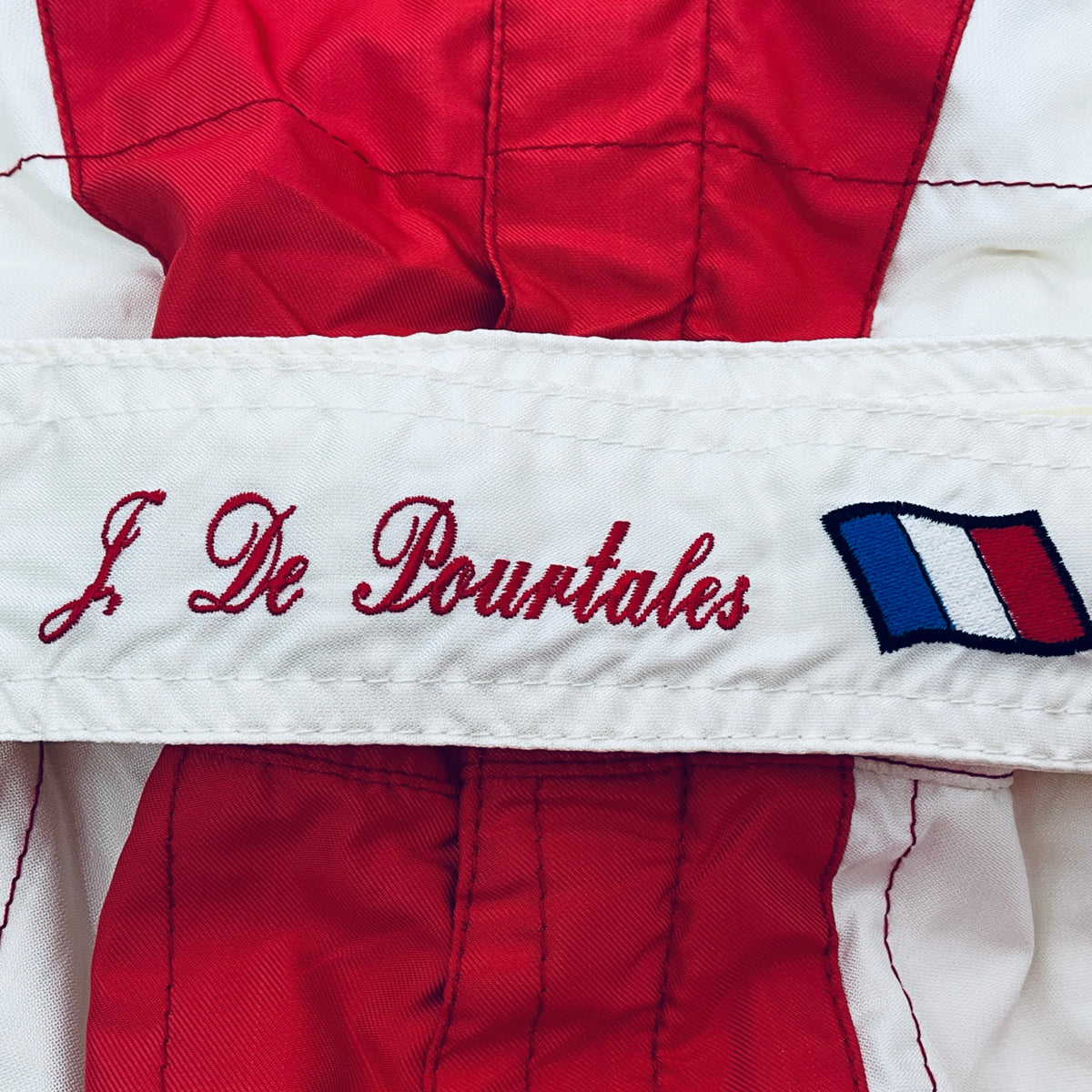 Jean de Pourtalès race-worn driver suit close-up with embroidered name and French flag patch