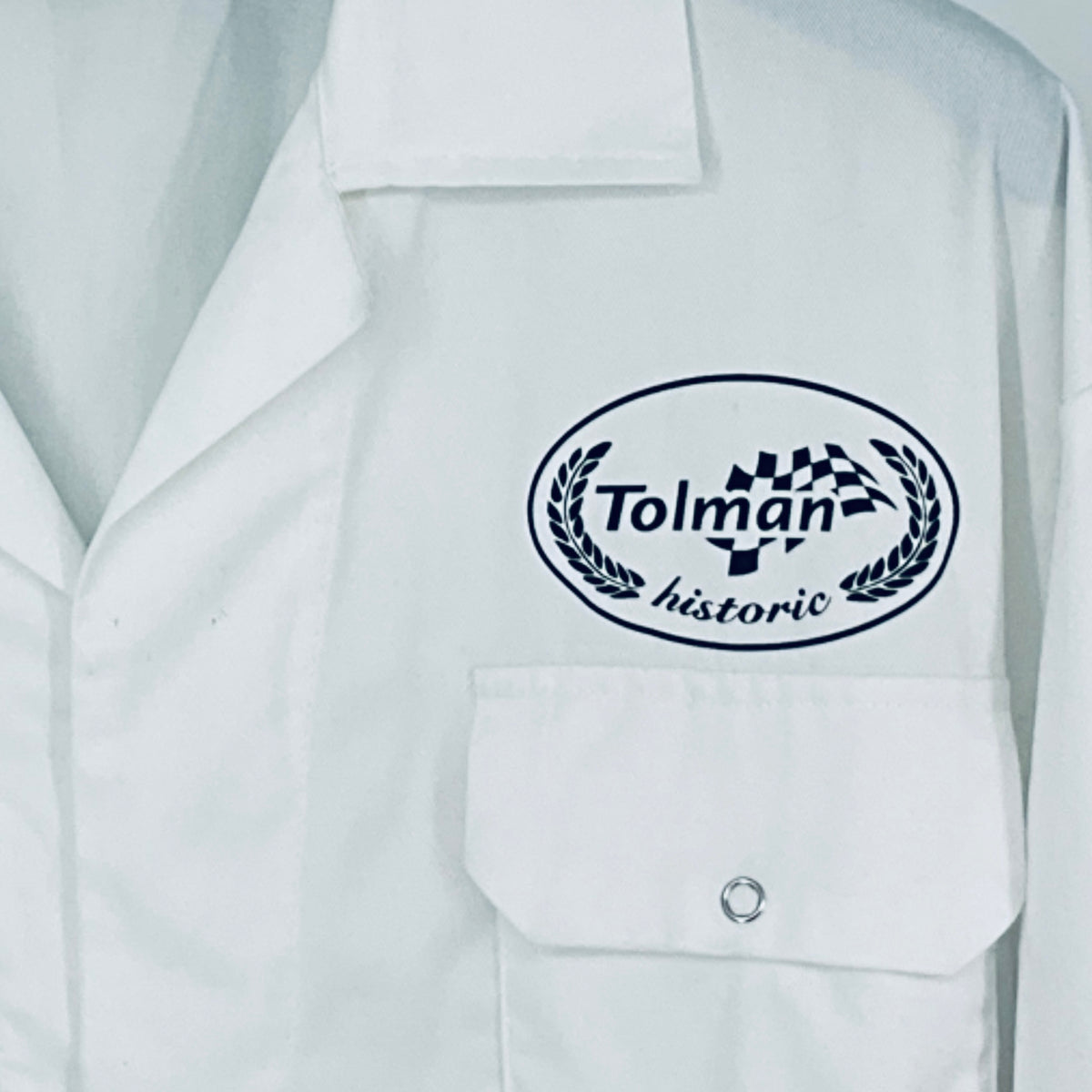 Close-up of Tolman historic logo patch on white overalls chest