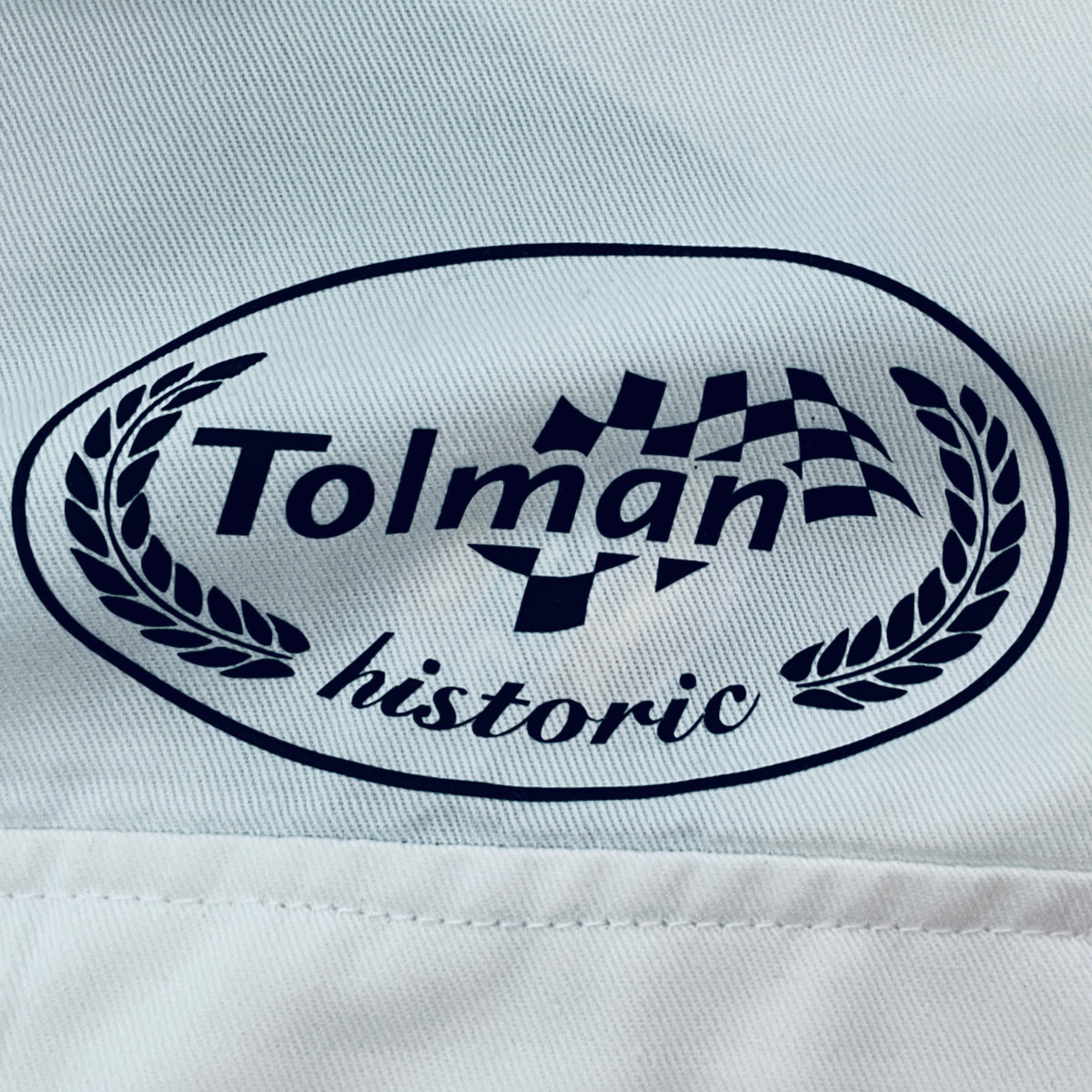 Embroidered Tolman historic logo on white overalls fabric