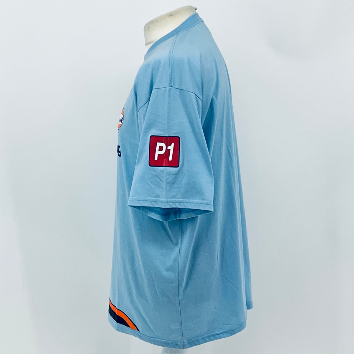 Light blue T-shirt back/side with red 'P1' patch and orange-dark blue hem stripe