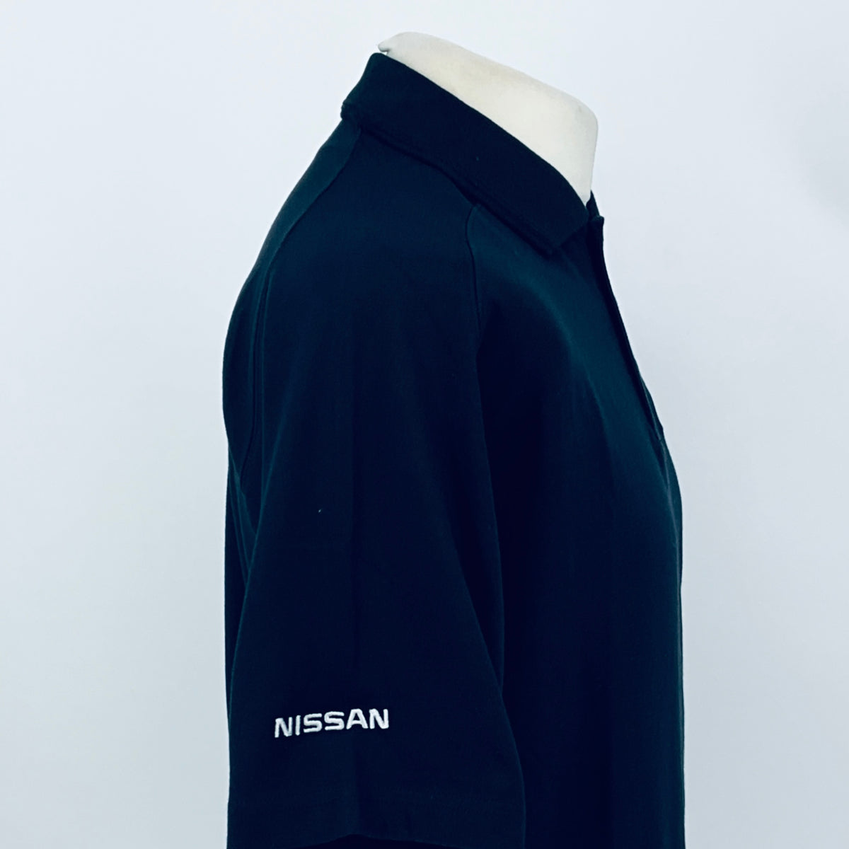Black polo shirt sleeve with Nissan logo patch