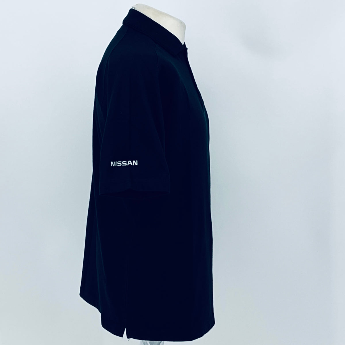 Black polo shirt sleeve with Nissan logo text