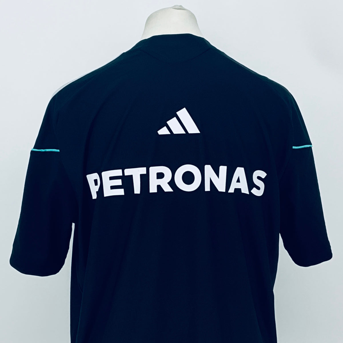 Navy F1 team t-shirt back showing PETRONAS lettering and adidas mark near the neck.