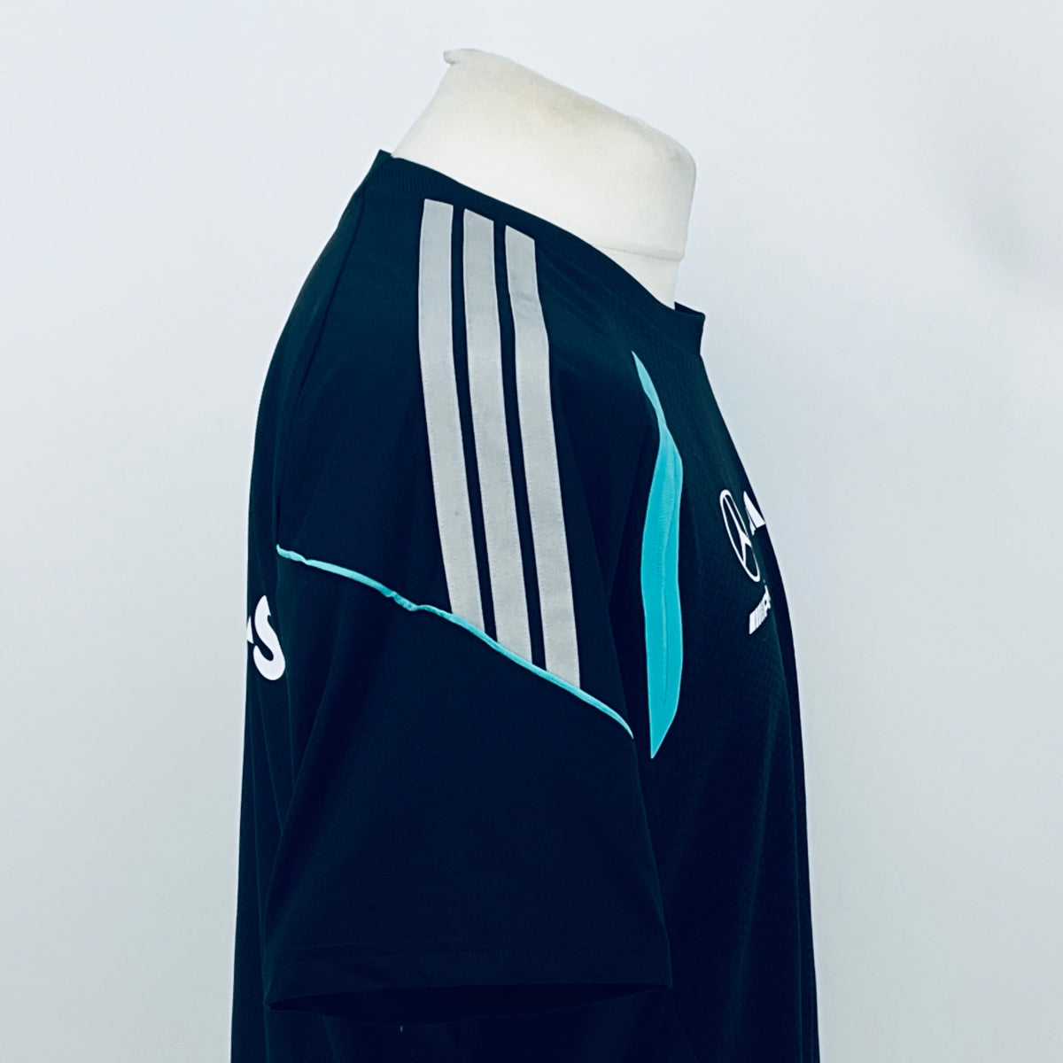 Navy F1 team t-shirt rear side with white vertical stripes and teal badge graphic.