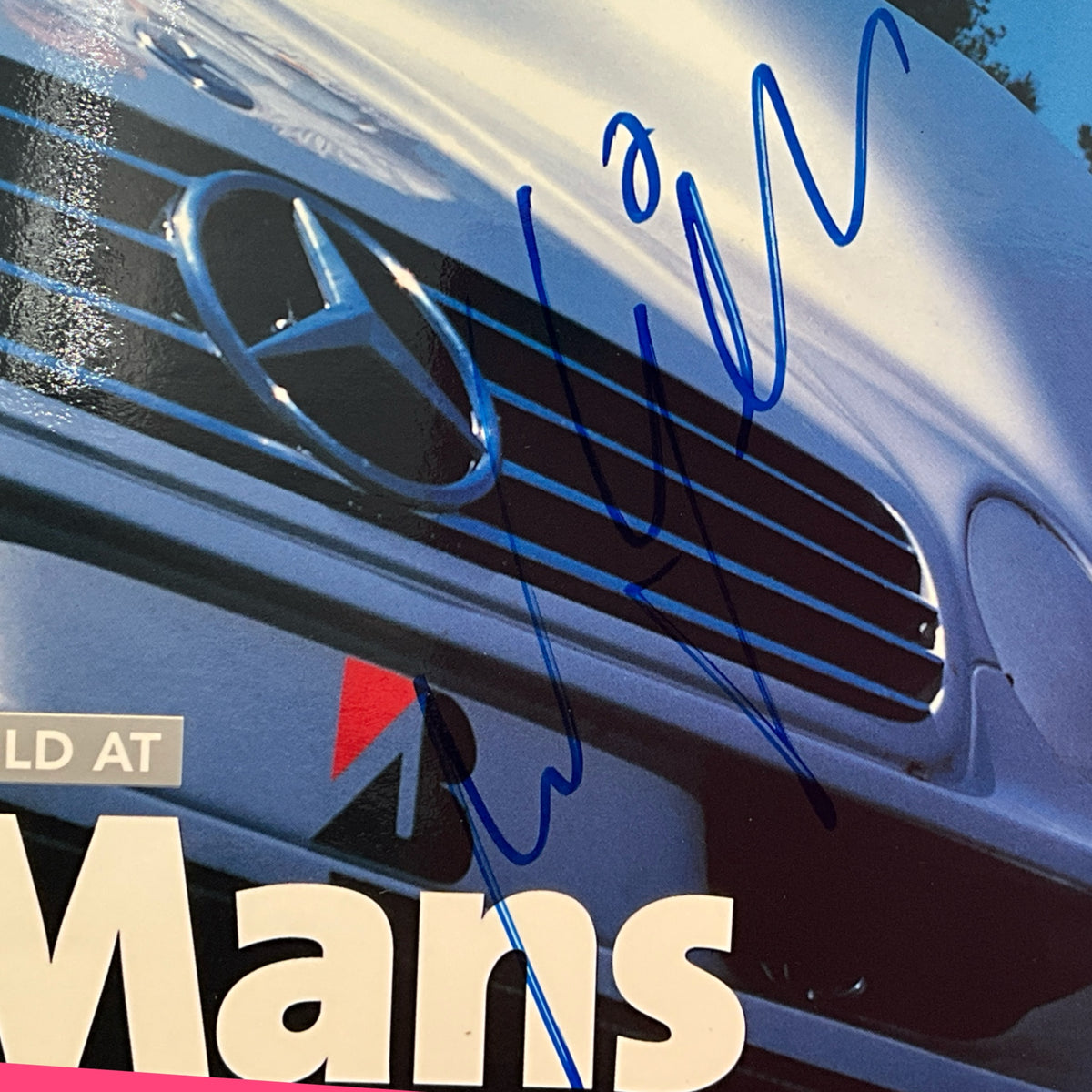 Racing magazine cover close-up of blue race car front grille and signature
